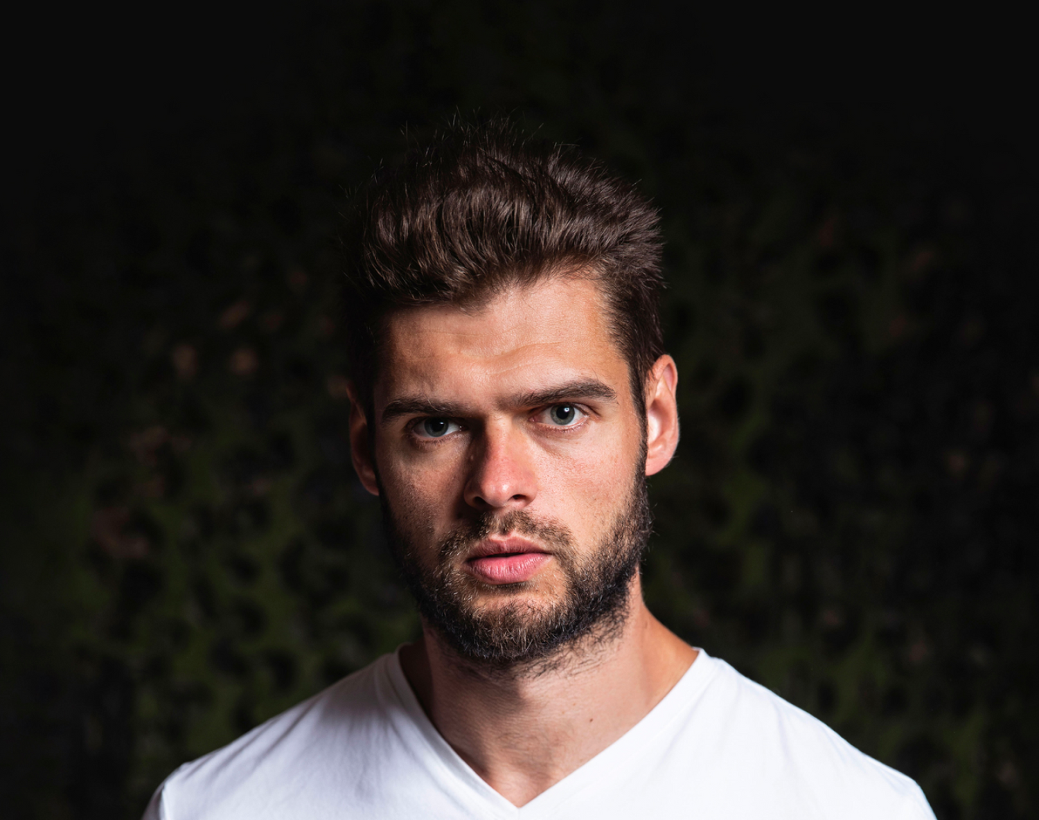 A man wearing a white t-shirt standing in front of a black background